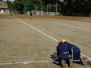 巻き尺を押さえる６年生とラインを引く本校職員(7:45)