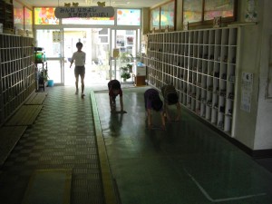 本館校舎玄関をぞうきんがけする子どもたち