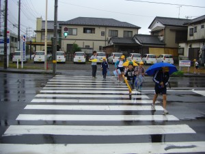 傘をさしながら鹿島小前交差点を渡る子どもたち(7:45)