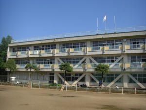 新館校舎と花壇で草取りをする飼育・園芸委員会の子どもたち(8:00)