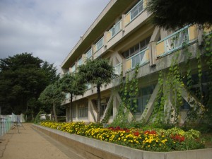 朝日に照らされる新館校舎　マリーゴールドやサルビアの花がきれいですね。(8:20)