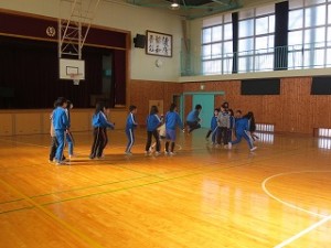 IMG_2991 体育館の一番奥ステージ前で練習をしています。全校児童が3つに分かれています。\