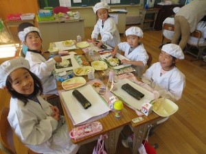 IMG_3074 1年生です。子どもたちの体と比べて,恵方巻きがとても大きく見えます。\